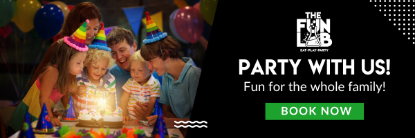 Family in party hats smiles around a lit cake. Colorful balloons in the background. Celebrating a birthday party at The Fun Lab Center in Blaine, MN. Text: "Party with us! Fun for the whole family! Book now."