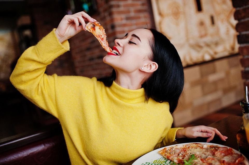 an adult girl eating pizza at the fun lab